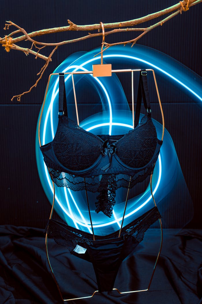 project-03-d Stylish black lingerie set on a hanger illuminated by vibrant neon lights in a studio shoot.